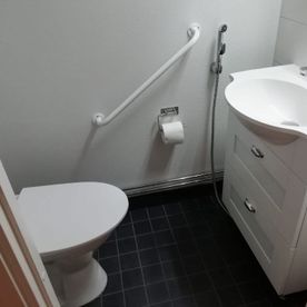 WC valkoisella seinällä ja tummalla lattialla